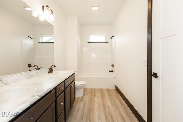 1511 Pistolero Way, Belgrade, MT 59714 - bathroom featuring wood finished floors, washtub / shower combination, toilet, double vanity, and plenty of natural light