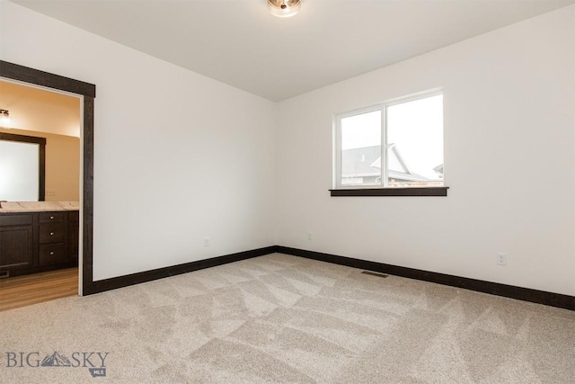 1511 Pistolero Way, Belgrade, MT 59714 - unfurnished bedroom with light colored carpet, baseboards, and ensuite bath