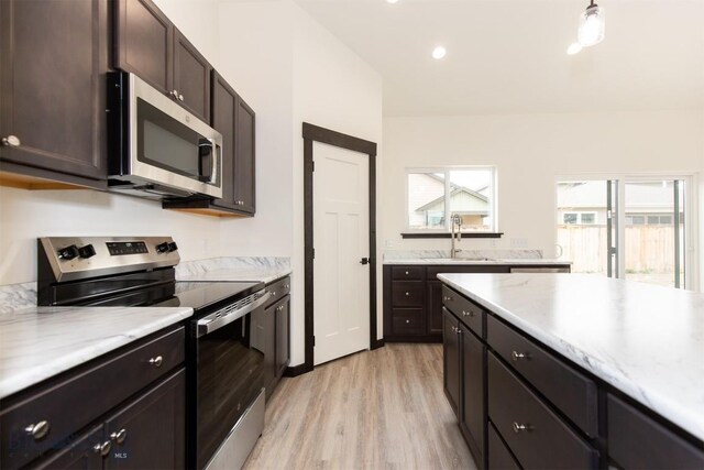 1511 Pistolero Way, Belgrade, MT 59714 - kitchen with appliances with stainless steel finishes, a sink, light wood-style flooring, light countertops, and dark brown cabinets