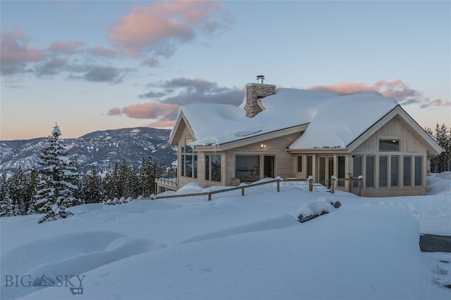 snow covered property featuring a mountain view and a sunroom