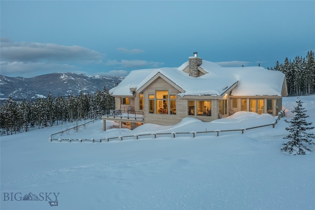 snow covered back of property featuring a mountain view