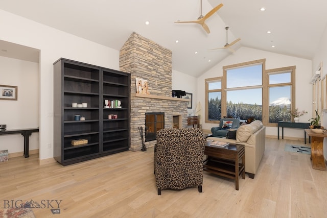 living room with light wood-type flooring, a fireplace, ceiling fan, and high vaulted ceiling