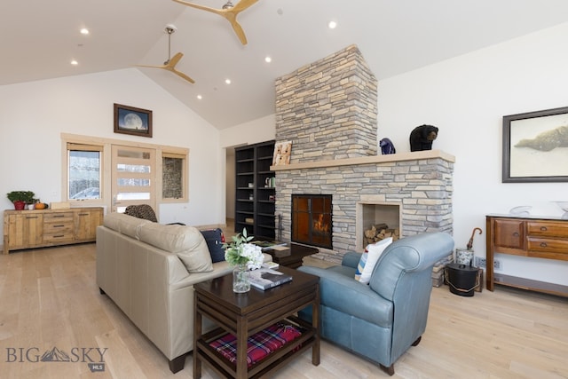 living room featuring a fireplace, light hardwood / wood-style floors, ceiling fan, and high vaulted ceiling