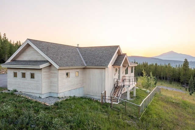 property exterior at dusk with a mountain view and a yard