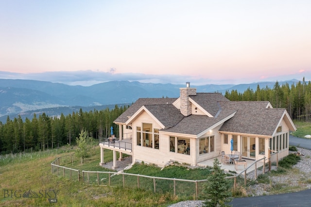 back house at dusk featuring a mountain view, a patio, and a balcony