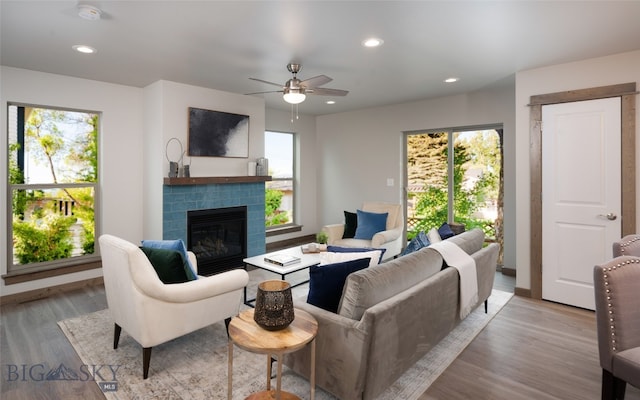 living room with a brick fireplace, plenty of natural light, and light hardwood / wood-style flooring