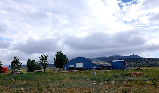 view of yard with an outbuilding, a rural view, and a mountain view