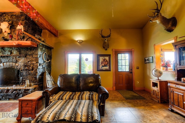 foyer entrance featuring a stone fireplace and beam ceiling