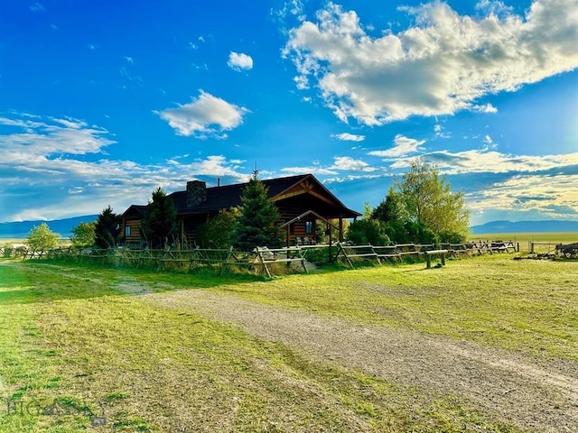 view of side of home with a mountain view, a rural view, and a lawn