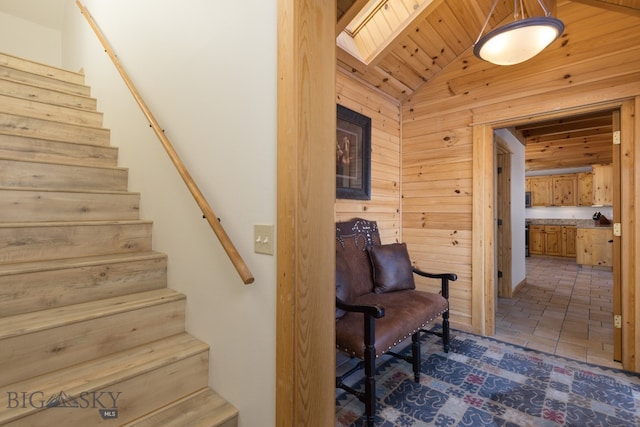 staircase featuring tile patterned flooring, wooden walls, vaulted ceiling with skylight, and wooden ceiling