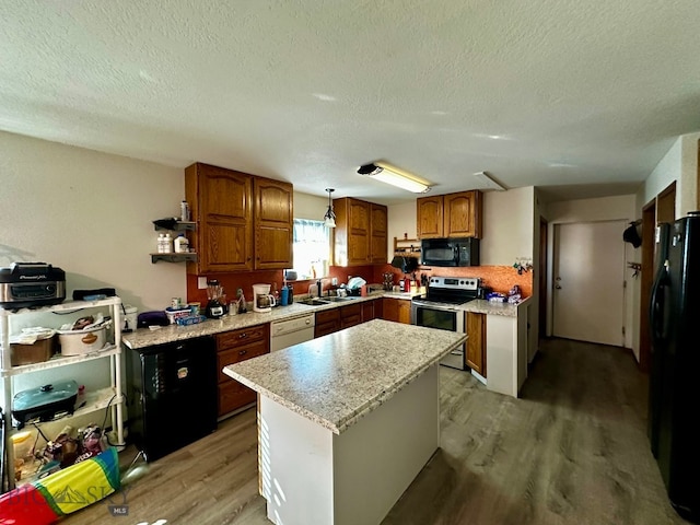 kitchen with light hardwood / wood-style floors, black appliances, a textured ceiling, and a kitchen island