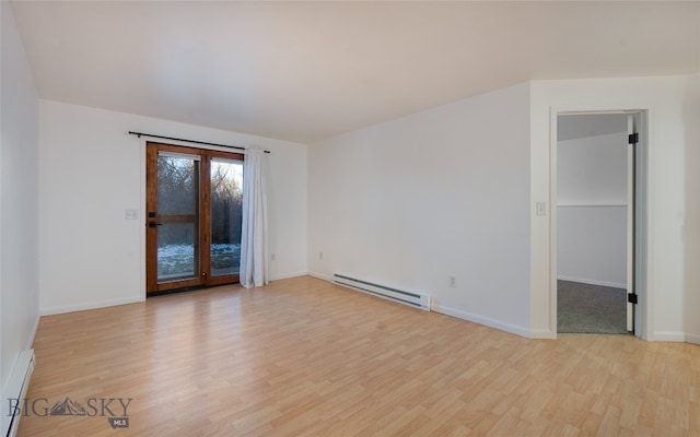 unfurnished room featuring a baseboard heating unit and light wood-type flooring