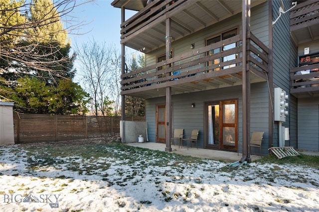 snow covered back of property with a patio area