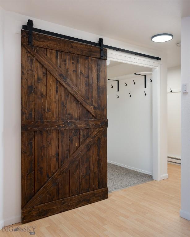 interior space featuring a barn door, light wood-type flooring, and baseboard heating