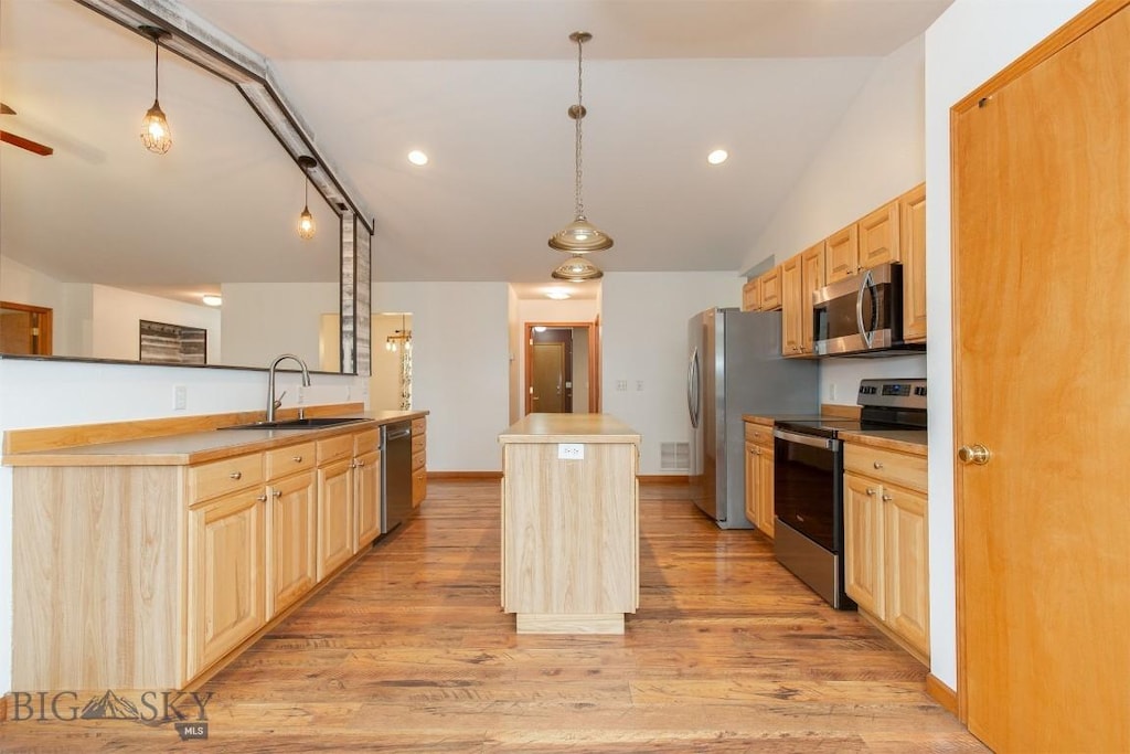 kitchen featuring decorative light fixtures, sink, appliances with stainless steel finishes, and a center island