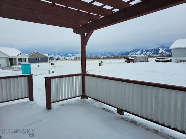 snow covered patio featuring a mountain view and a pergola