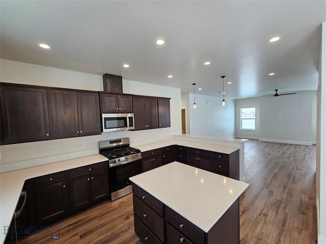 kitchen with appliances with stainless steel finishes, open floor plan, light countertops, and decorative light fixtures