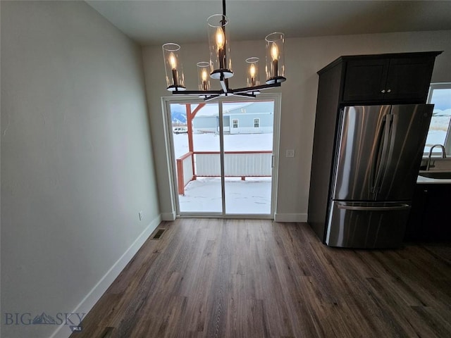 unfurnished dining area with dark wood-type flooring, a sink, and baseboards