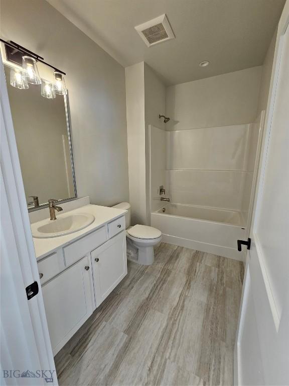 full bathroom featuring visible vents, toilet, vanity, shower / tub combination, and wood finished floors