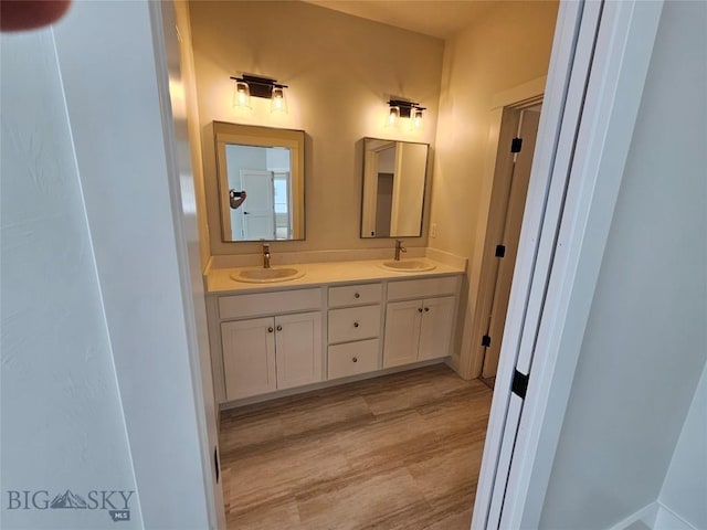 bathroom featuring double vanity, a sink, and wood finished floors