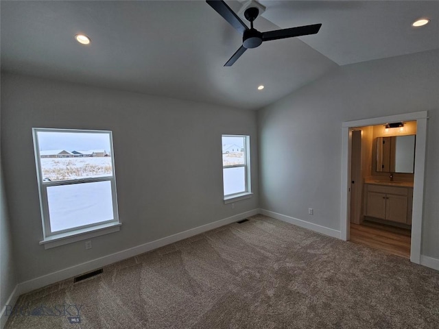 unfurnished bedroom with lofted ceiling, a sink, carpet flooring, baseboards, and visible vents