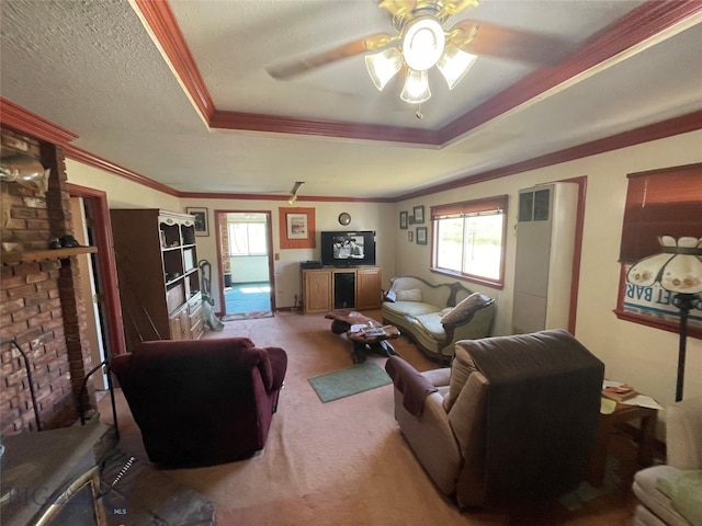 carpeted living room featuring a raised ceiling, ceiling fan, plenty of natural light, and ornamental molding