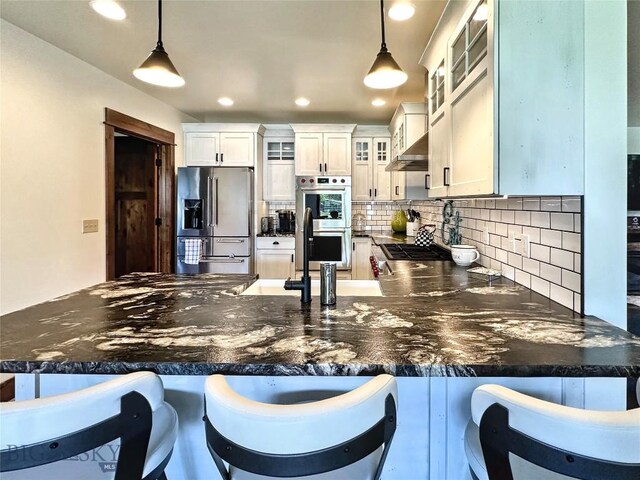 401 Mill Crk, Sheridan, MT 59749 - kitchen featuring appliances with stainless steel finishes, a peninsula, backsplash, glass insert cabinets, and wall chimney range hood
