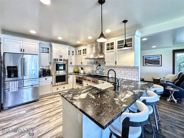401 Mill Crk, Sheridan, MT 59749 - kitchen with appliances with stainless steel finishes, wall chimney exhaust hood, a peninsula, light wood-type flooring, and recessed lighting