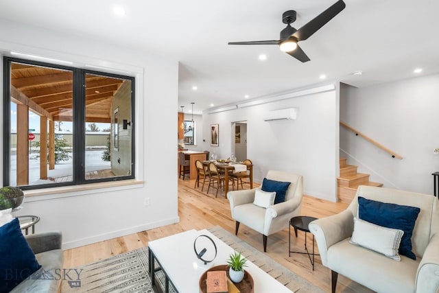 living room featuring ceiling fan, a wall mounted air conditioner, and light hardwood / wood-style floors