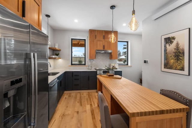 kitchen featuring tasteful backsplash, decorative light fixtures, a center island, stainless steel fridge, and black dishwasher