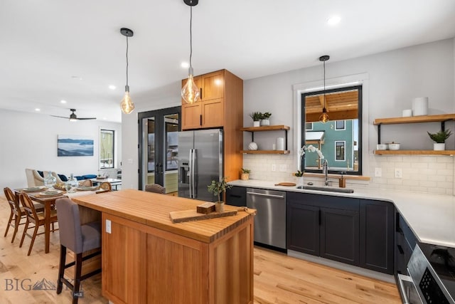 kitchen featuring pendant lighting, appliances with stainless steel finishes, sink, and decorative backsplash