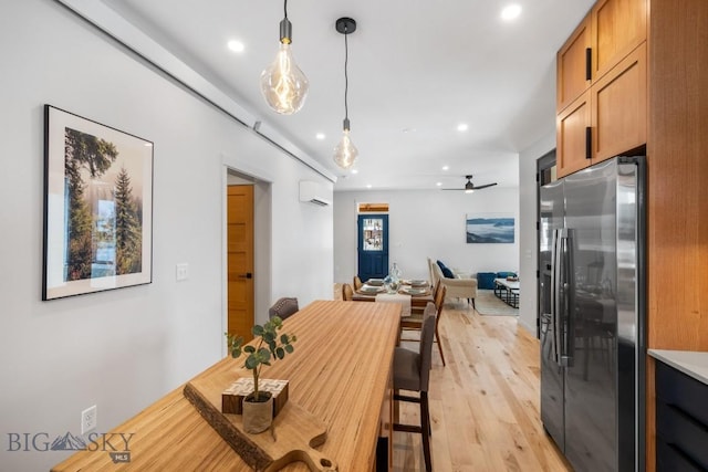 dining space with a wall mounted air conditioner, ceiling fan, and light wood-type flooring