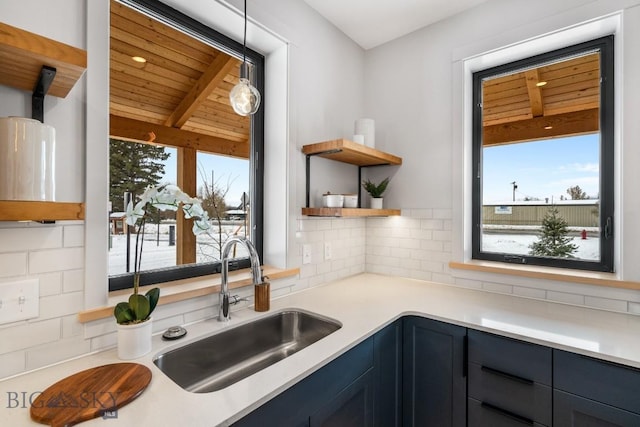 kitchen with blue cabinetry, sink, hanging light fixtures, wooden ceiling, and decorative backsplash