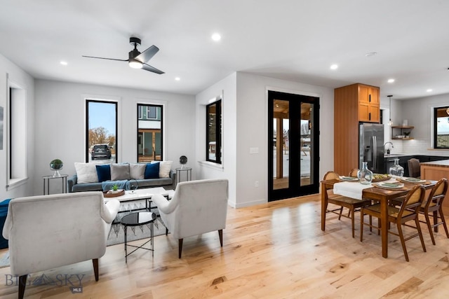 dining room featuring ceiling fan, a healthy amount of sunlight, light wood-type flooring, and french doors