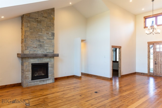 unfurnished living room with a chandelier, high vaulted ceiling, a healthy amount of sunlight, and light hardwood / wood-style floors