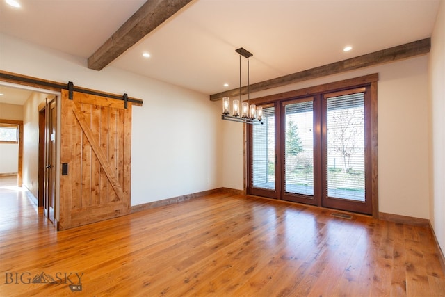 interior space featuring beam ceiling, a barn door, a notable chandelier, and hardwood / wood-style flooring