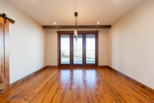 unfurnished dining area with a barn door and light hardwood / wood-style flooring