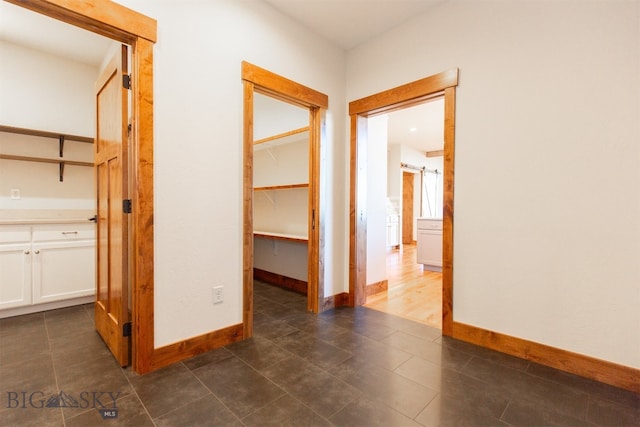 corridor with dark tile patterned flooring and a barn door