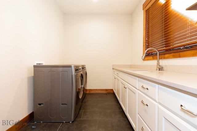 clothes washing area featuring washing machine and dryer, sink, cabinets, and dark tile patterned flooring