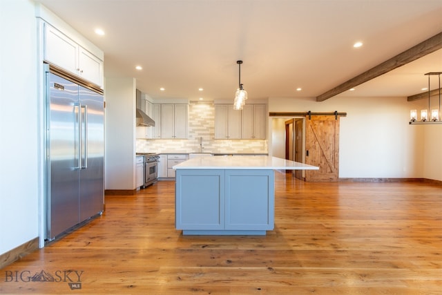 kitchen featuring hanging light fixtures, a barn door, light wood-type flooring, premium appliances, and a kitchen island