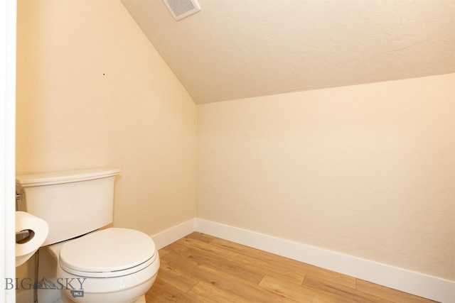 bathroom with toilet, wood-type flooring, and vaulted ceiling