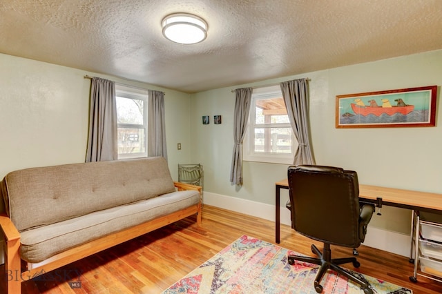 home office featuring plenty of natural light, wood-type flooring, and a textured ceiling