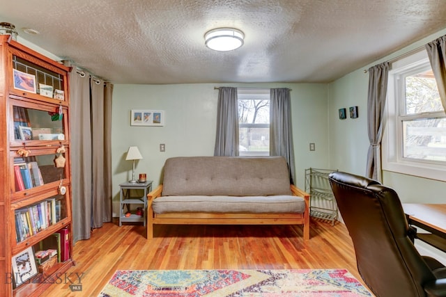 sitting room featuring radiator heating unit, light wood-type flooring, and a textured ceiling