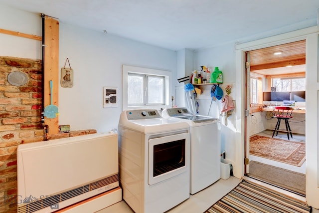 laundry area featuring plenty of natural light, independent washer and dryer, and brick wall