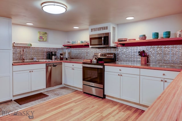 kitchen featuring butcher block counters, stainless steel appliances, light hardwood / wood-style floors, decorative backsplash, and white cabinets