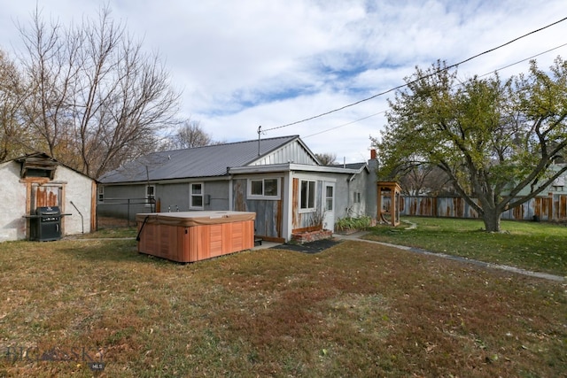 back of house featuring a hot tub and a lawn