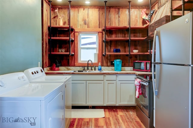 interior space with white cabinets, sink, independent washer and dryer, light wood-type flooring, and stainless steel appliances