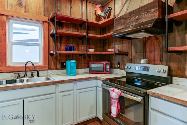 kitchen with custom range hood, sink, white cabinetry, and electric stove