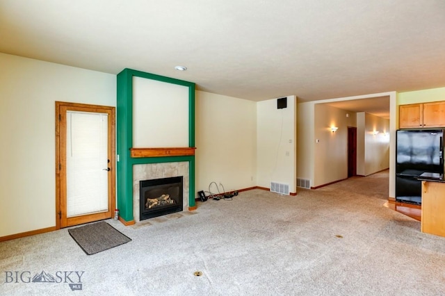 unfurnished living room featuring light carpet and a tiled fireplace