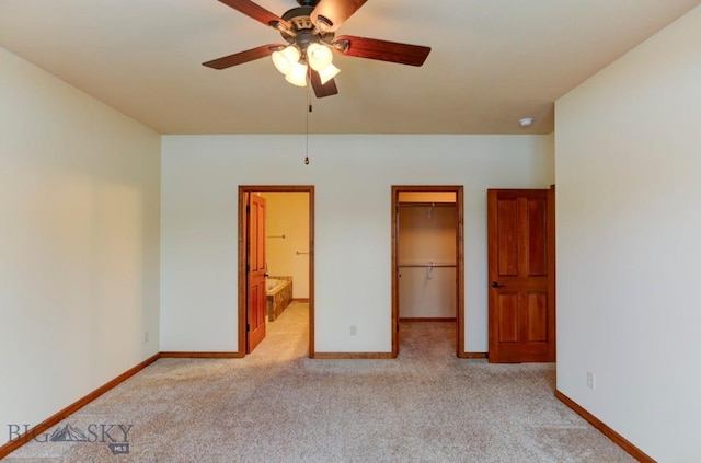 unfurnished bedroom featuring ensuite bath, ceiling fan, light colored carpet, a walk in closet, and a closet